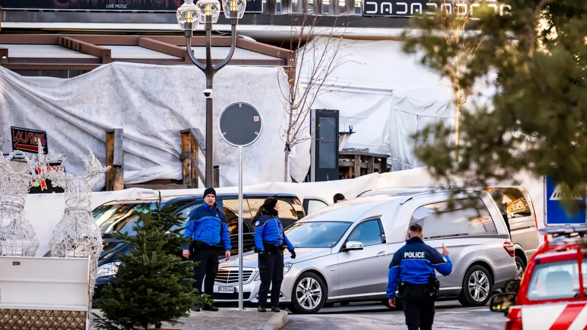 A hearse car drives as police officers inspect the area where a fire broke out at the Le Constellation bar and lounge during New Year's celebration, in Crans-Montana, Switzerland, Thursday, Jan. 1, 2026. (Jean-Christophe Bott/Keystone via AP)